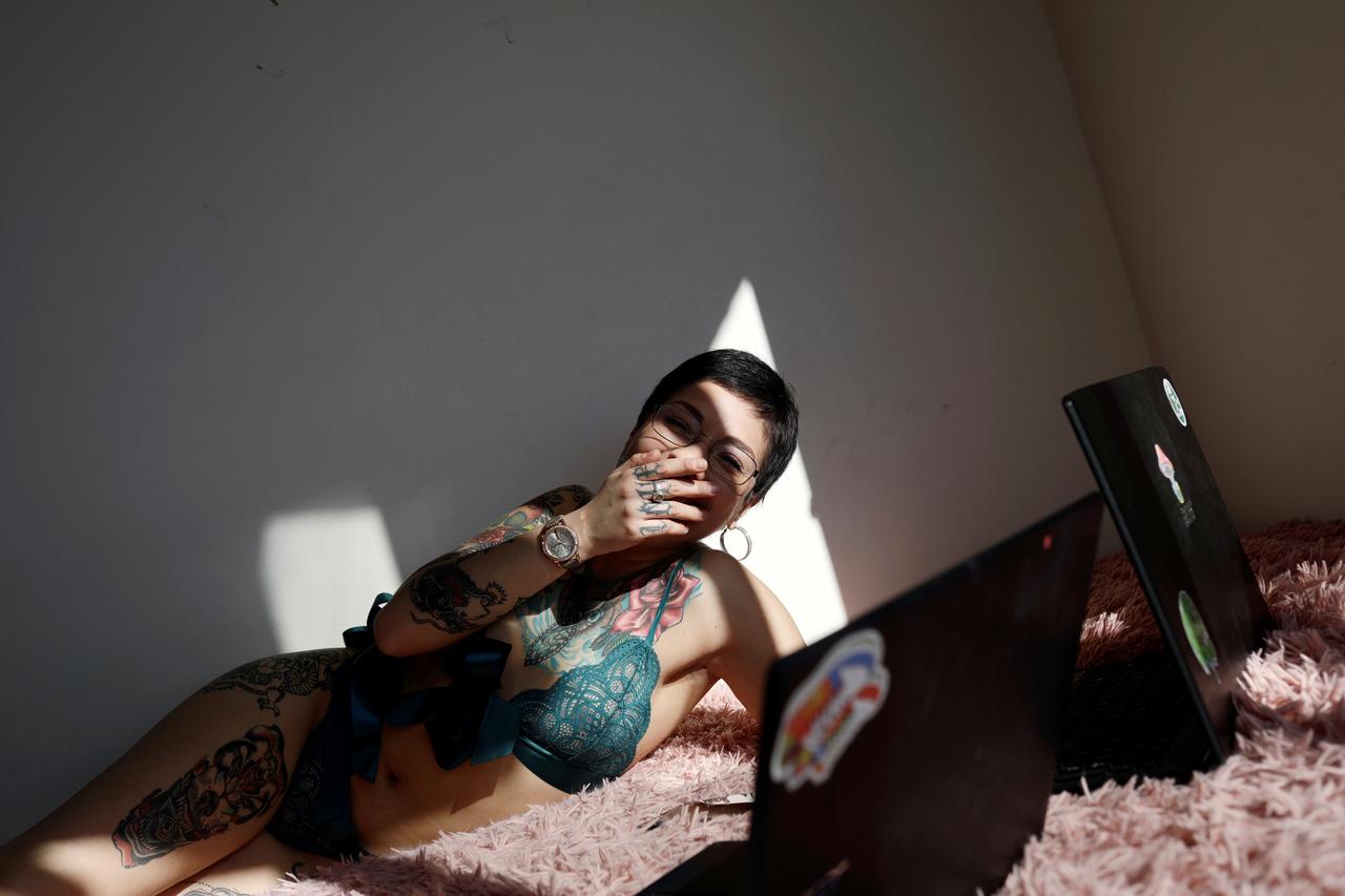Camila Hormazabal, a 24-year-old sex worker, uses laptops to connect to the web and keep an online erotic meeting with a virtual customer in Concepcion, Chile April 7, 2020. Hormazabal reinvented herself offering sexual services online after the nightclub where she had worked was closed due to the outbreak of the coronavirus disease (COVID-19). Picture taken April 7, 2020. REUTERS/Juan Gonzalez
