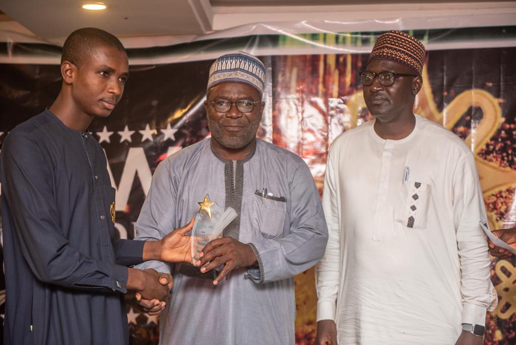 Publisher of SolaceBase, Mr. Abdullateed Jos Present Young Innovator Award Engr Mustapha Gajibo who produced electric vehicle in Borno as Dr Kabir Sufi chair of the panel of jury watches on.