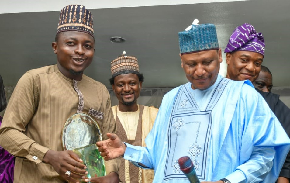 Umar Audu (left) receiving the award from the Minister of Information, Mohammed Malagi